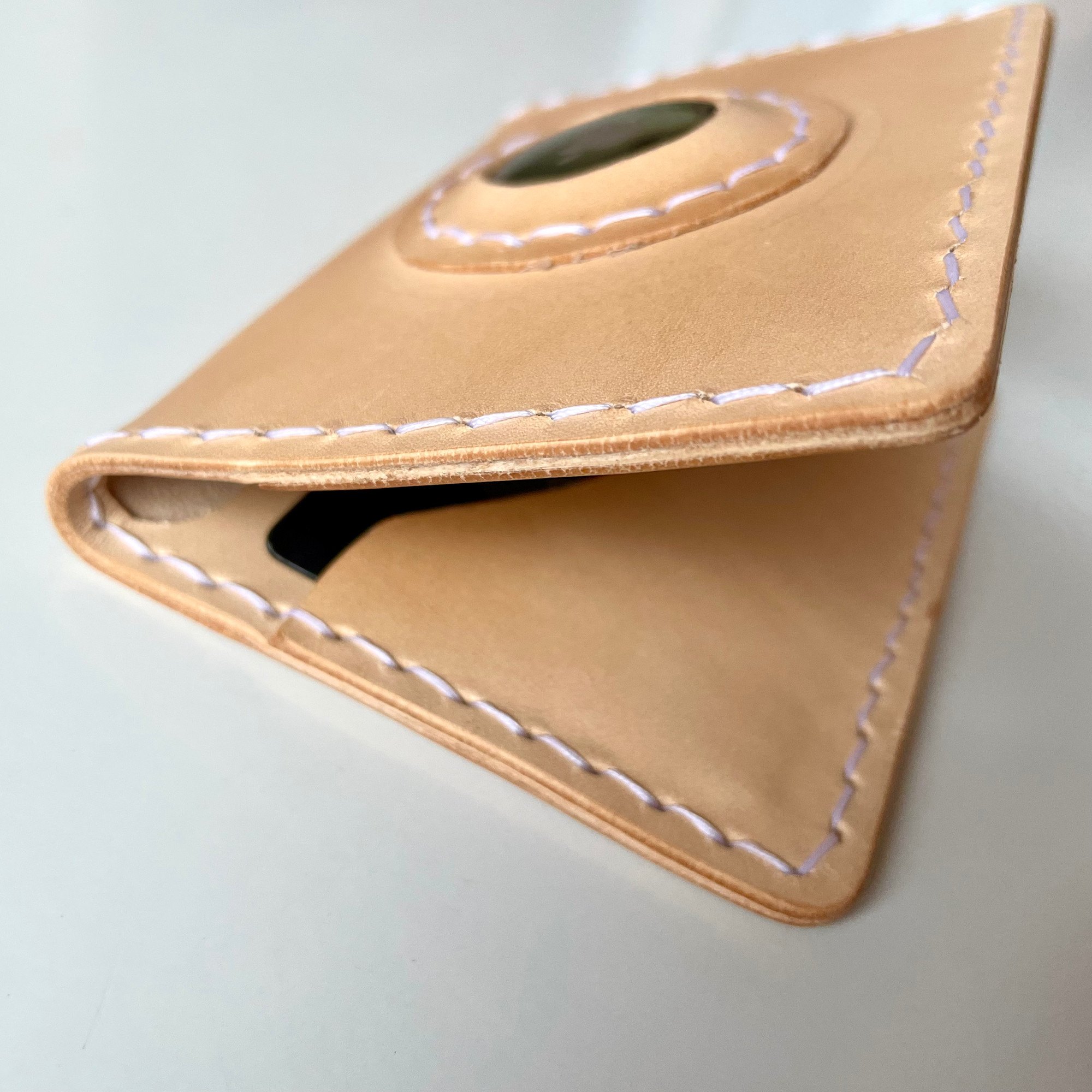 AirTag card wallet by 1985 Studio from the side, the window for the AirTag on top and a card inside the fold of vegetable-tanned leather